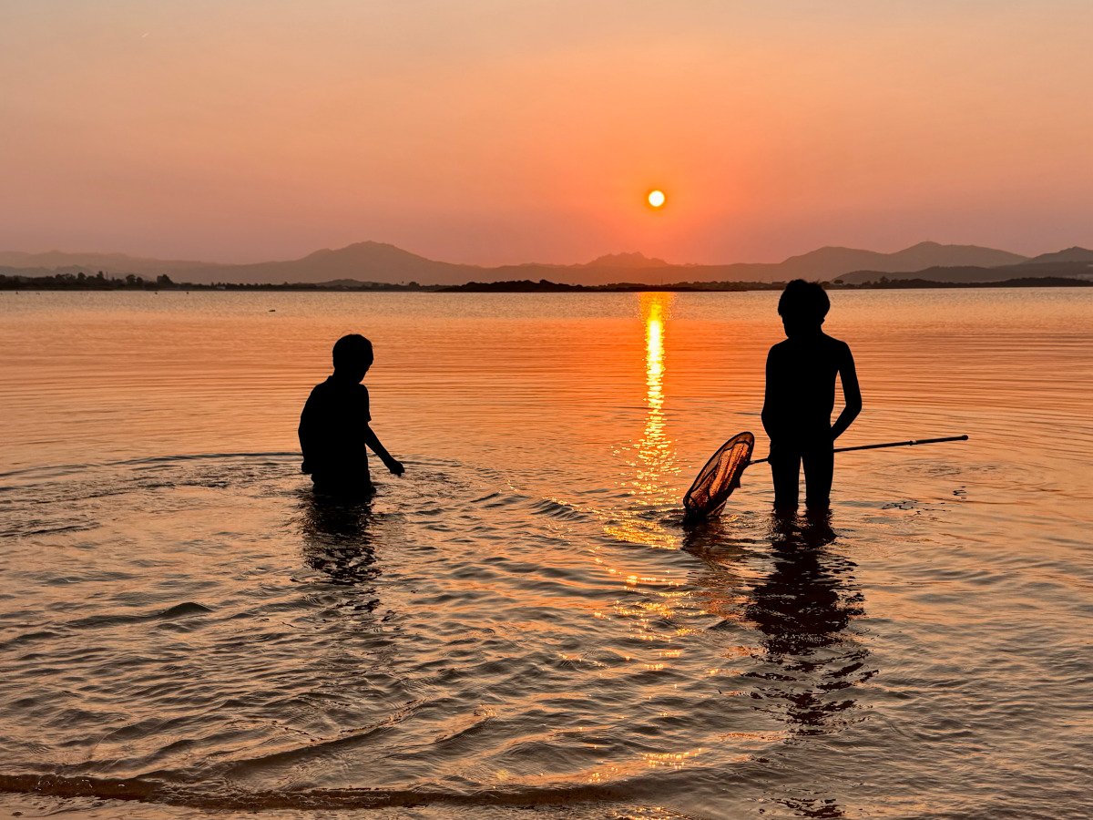 Children playing in the water at sunset in Porto San Paolo